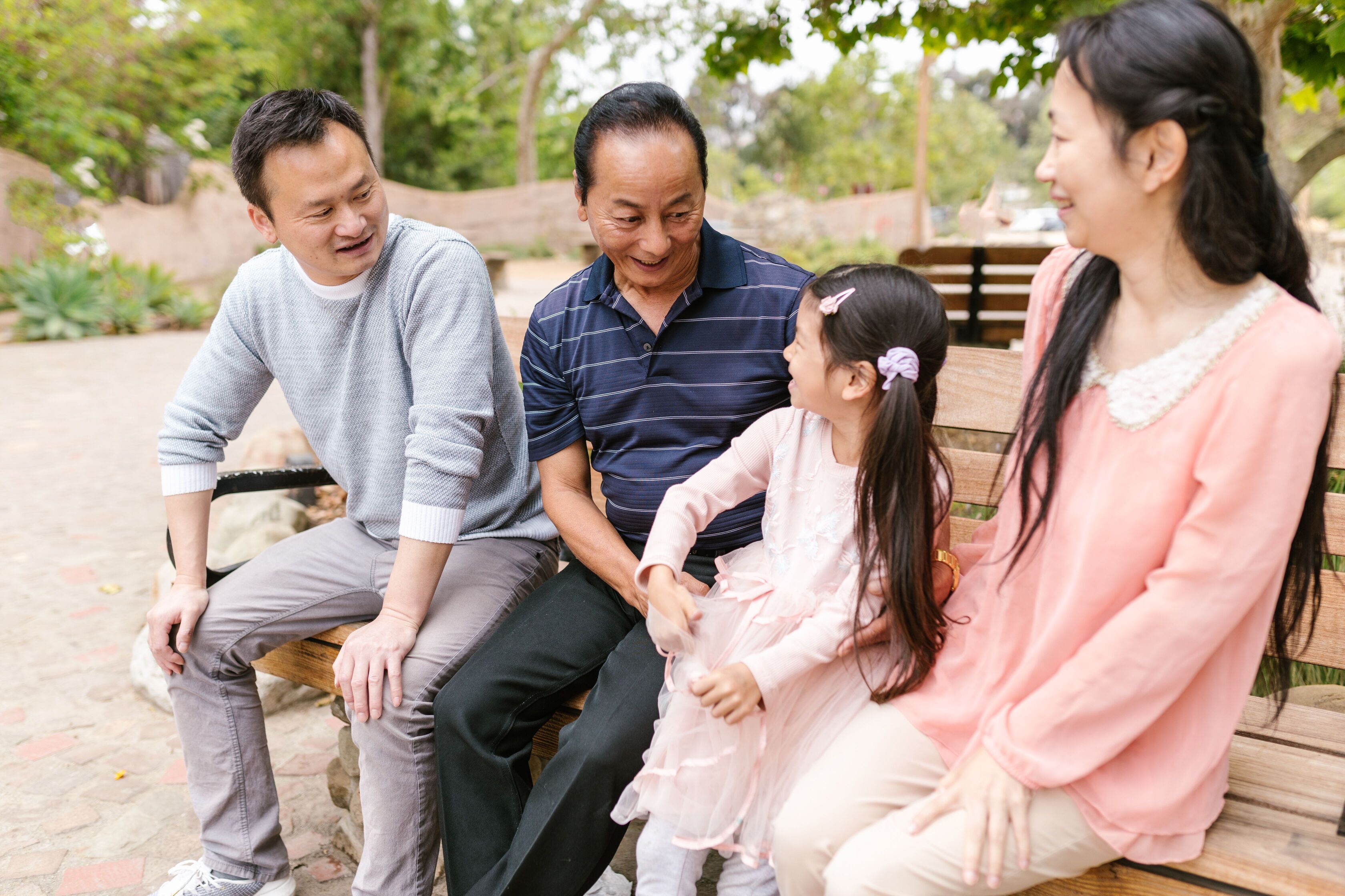 Three generations of a Thai family sitting together outdoors and smiling
